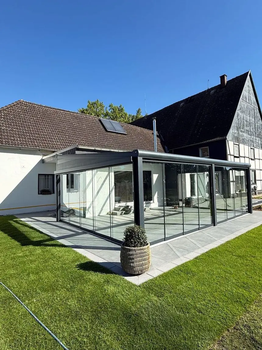 Fertiger Sommergarten aus Glas mit umlaufender Feinsteinzeug-Terrasse und Rollrasen